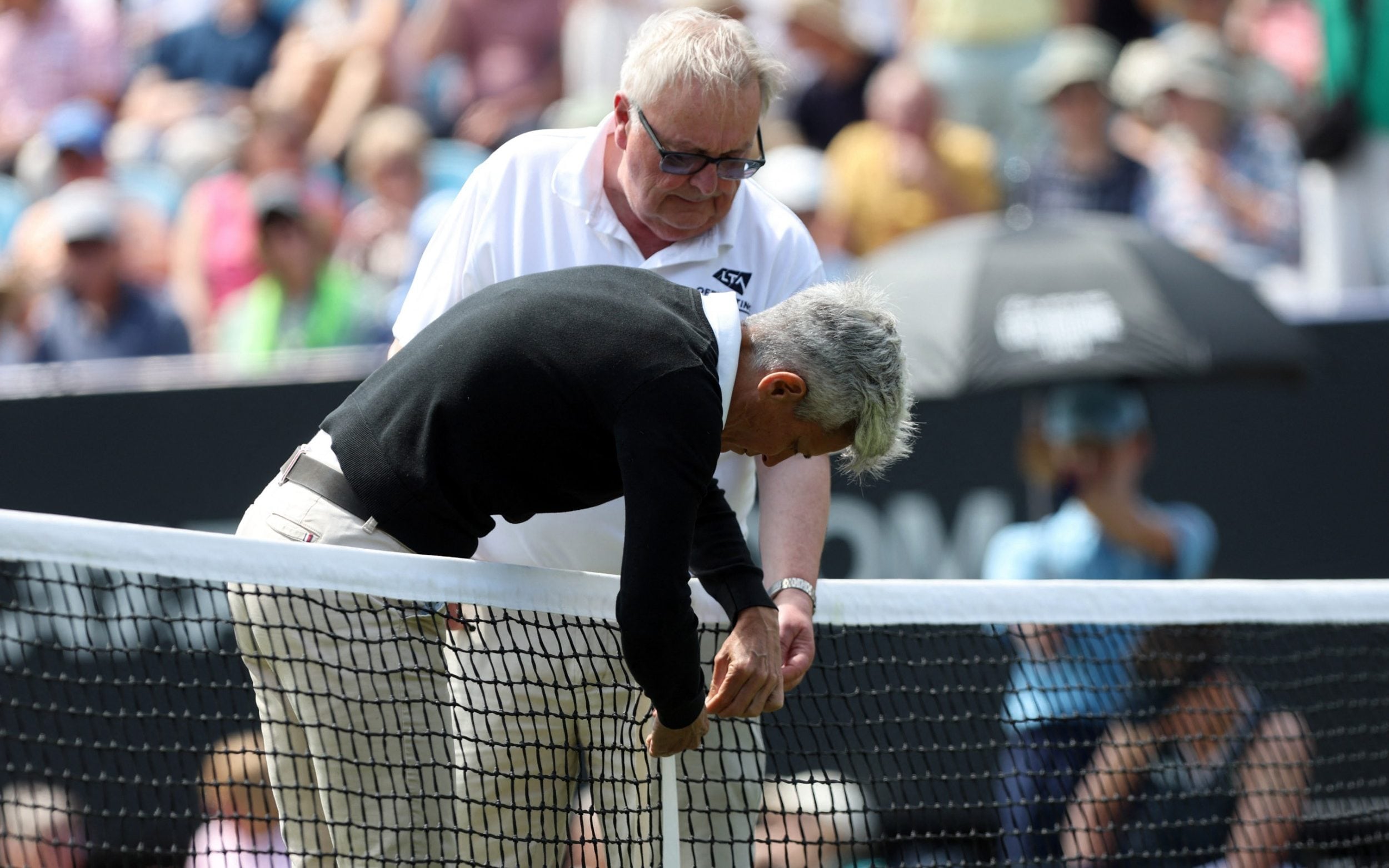 Umpire Marija Čičak and a member of groundstaff attend to the hole in the net