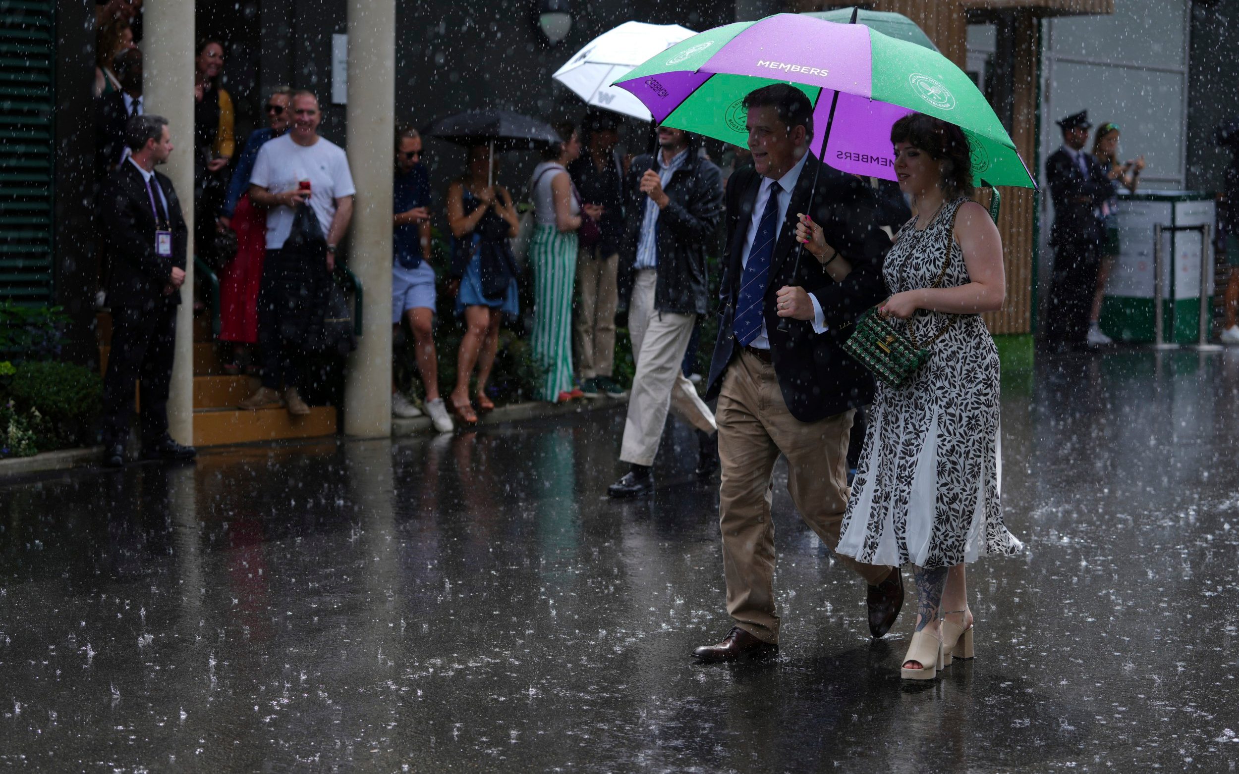 People walk through the heavy rain at Wimbledon